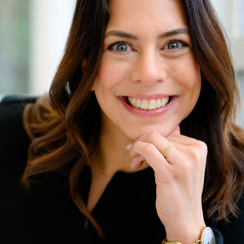 Melanie Schwarz - Coaching für Führungskräfte - stützt ihr Kinn auf die Hand und lächelt in die Kamera.